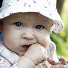 Color picture of baby girl chewing on a chicken bone.